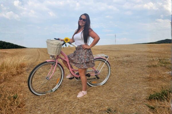 Žena s biciklom u polju sa suncokretom.